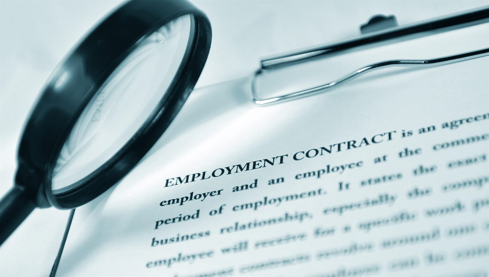 Magnifying glass and pen resting on an employment contract