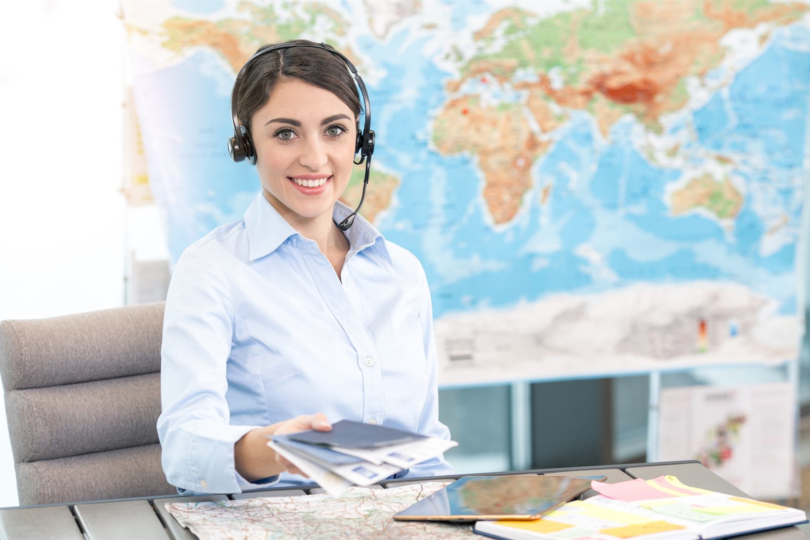 Travel consultant wearing a headset at a desk in front of a world map
