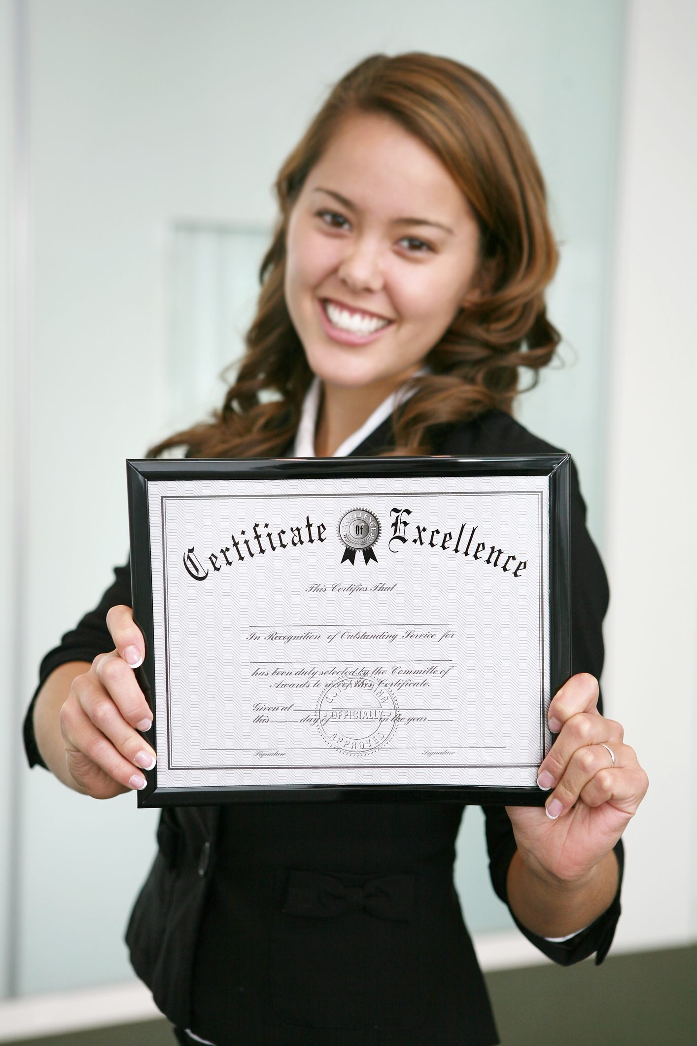 Smiling young professional holding up a framed training certificate